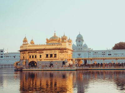 A serene view of the Golden Temple in Amritsar, its reflection shimmering in the tranquil water at sunrise.